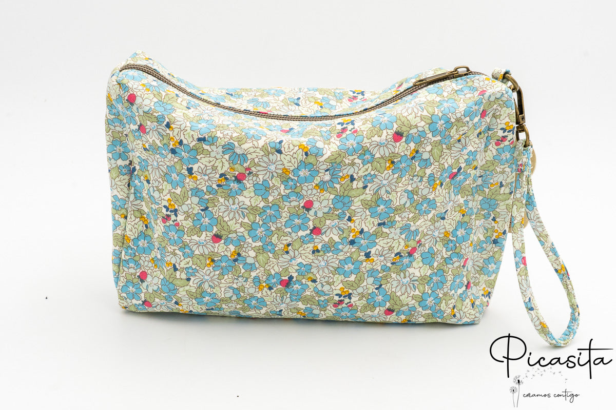 Neceser floral verde con asa lateral de la misma tela y cremallera superior metálica.