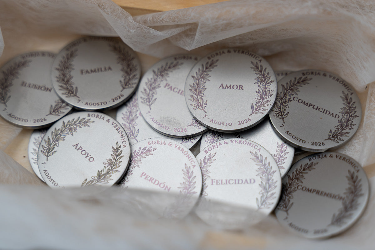 Detalle de monedas de boda grabadas con palabras como amor, familia y perdón.
