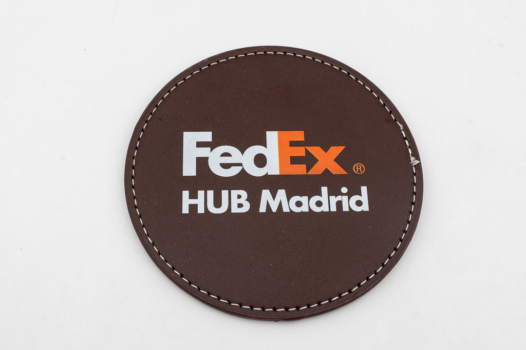 Sous-verre rond marron avec logo FedEx en couleur.