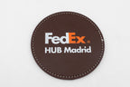 Sous-verre rond marron avec logo FedEx en couleur.