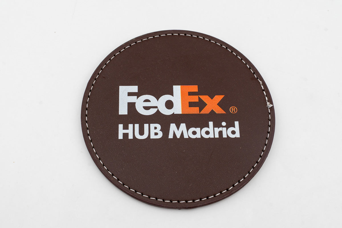 Sous-verre rond marron avec logo FedEx en couleur.