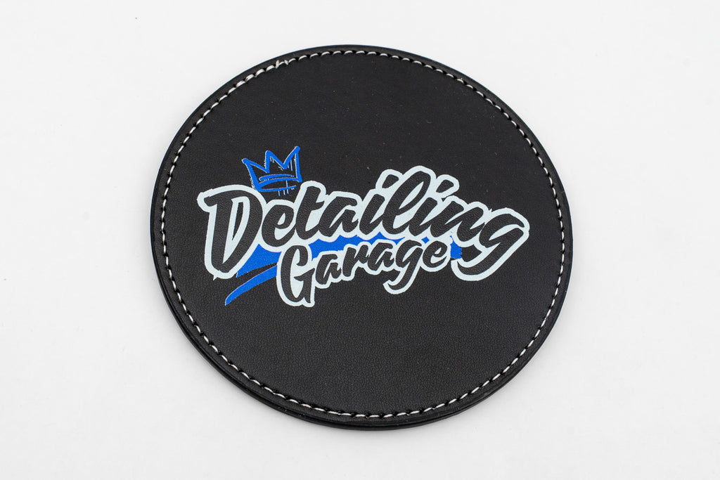Sous-verre rond noir avec logo Detailing Garage bleu et jaune.