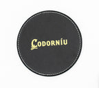 Sous-verre rond noir avec logo Codorníu de teinte dorée.