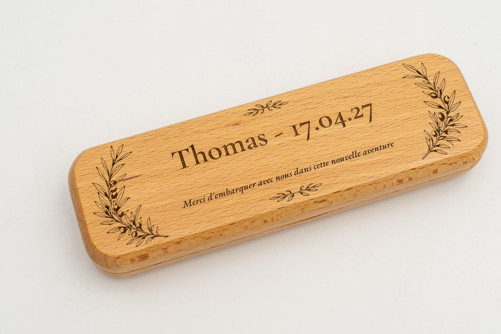 Étui en bois avec prénom, date et branches gravés sur le couvercle.