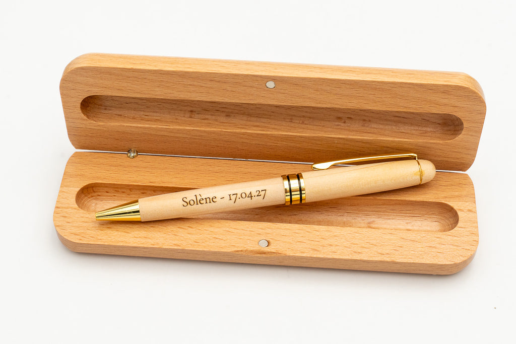 Étui ouvert avec stylo en bois clair à capuchon et détails dorés.