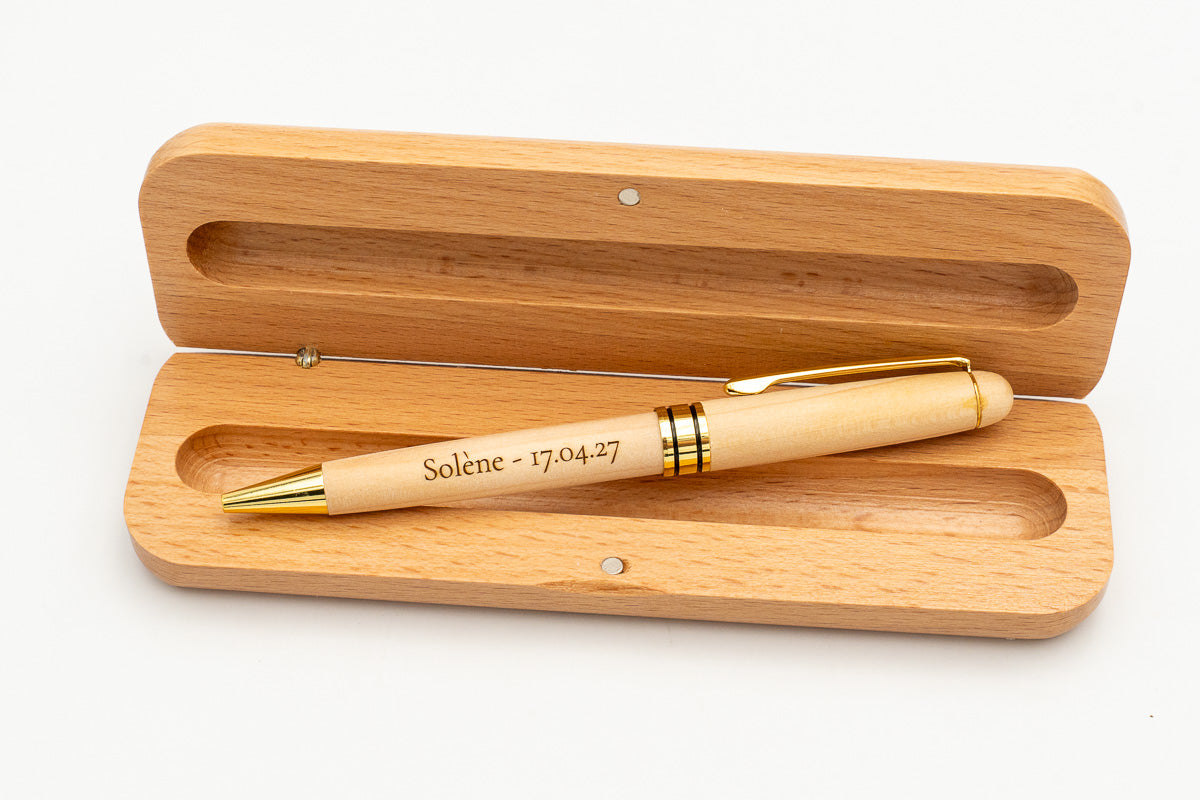 Étui ouvert avec stylo en bois clair à capuchon et détails dorés.