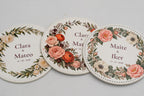 Trois sous-verres ronds blancs avec fleurs en couleur et prénoms de mariés.