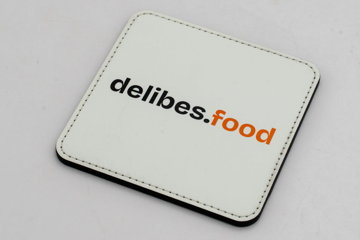 Sous-verre carré blanc avec logo delibes.Food noir et orange.