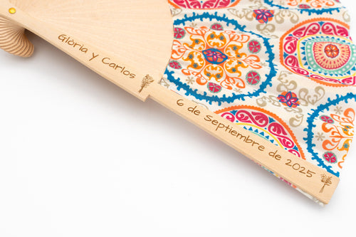 Éventail avec tissu à mandalas colorés et les noms Gloria et Carlos avec la date gravés dans le bois
