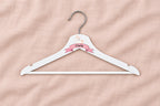 Percha infantil blanca con unicornio, cinta rosa y nombre Carla sobre lino rosa liso