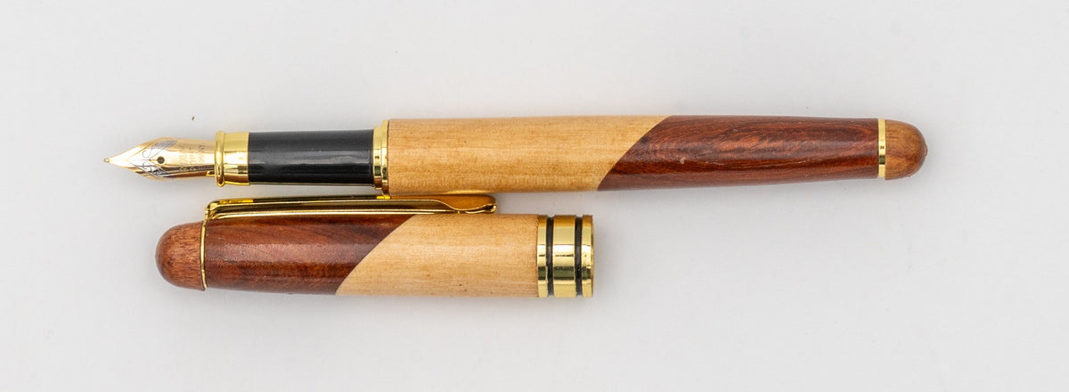 Stylo plume en bois bicolore avec capuchon retiré et plume visible.