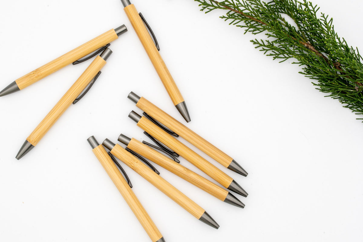 Stylos en bambou avec clip, bouton-poussoir et pointe gris sur fond blanc.