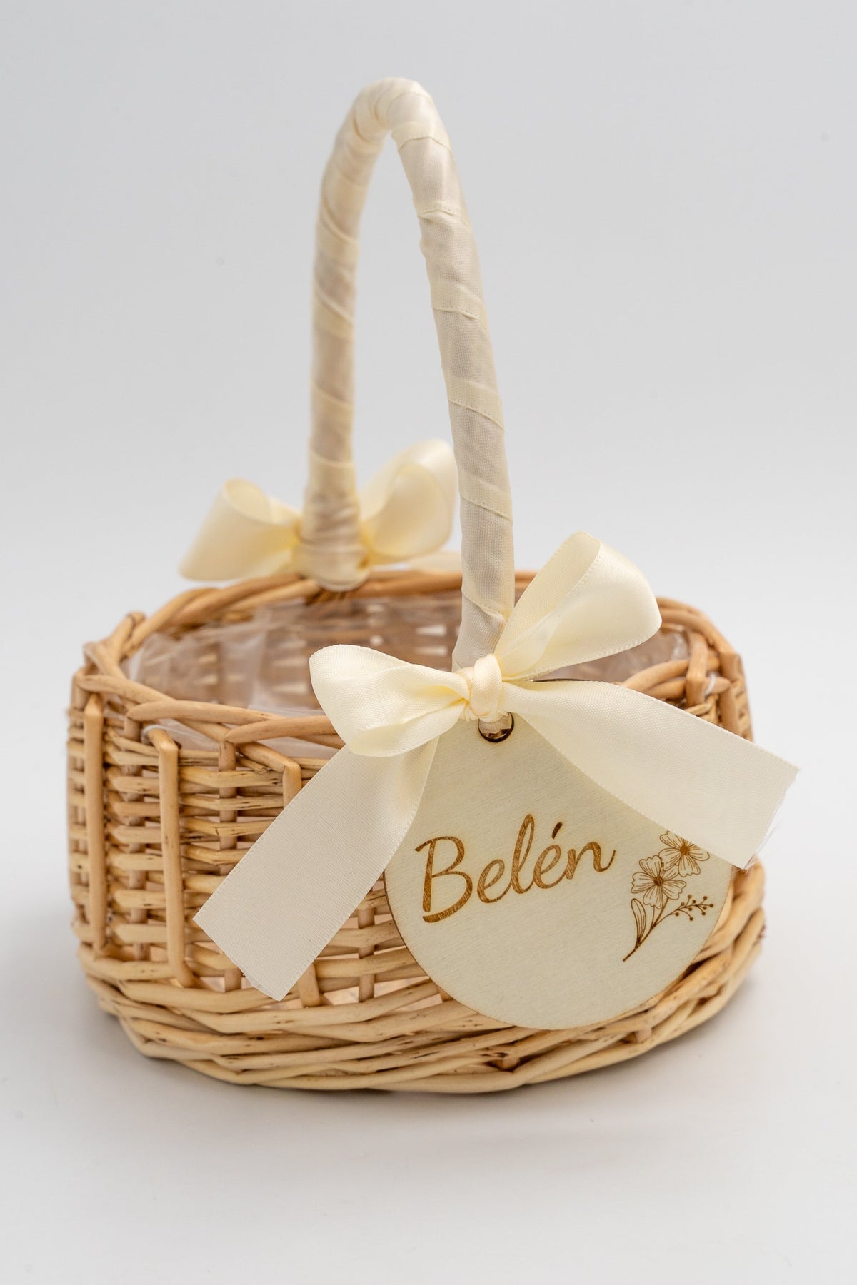 Panier artisanal en fibres naturelles avec nœud crème et détail botanique sur un disque en bois