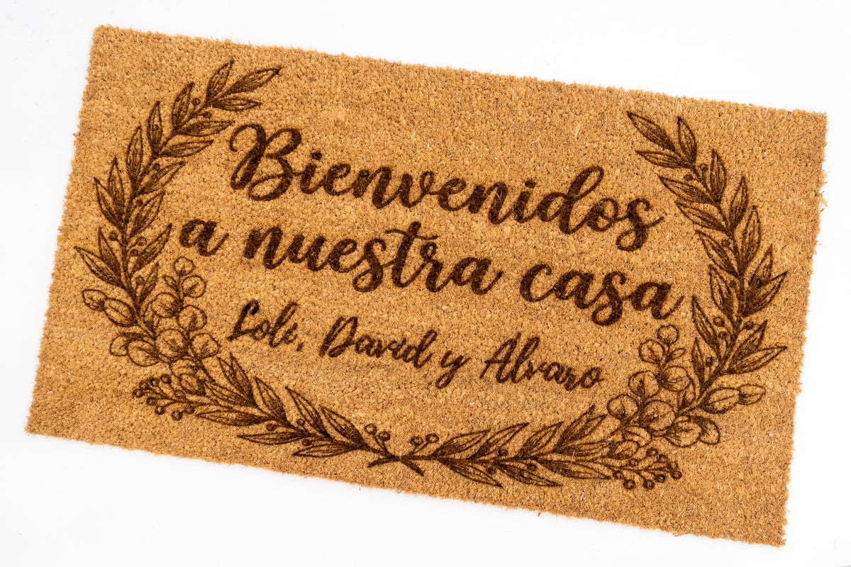 Detalle de felpudo personalizado con tipografía cursiva y elementos vegetales calados visualmente.