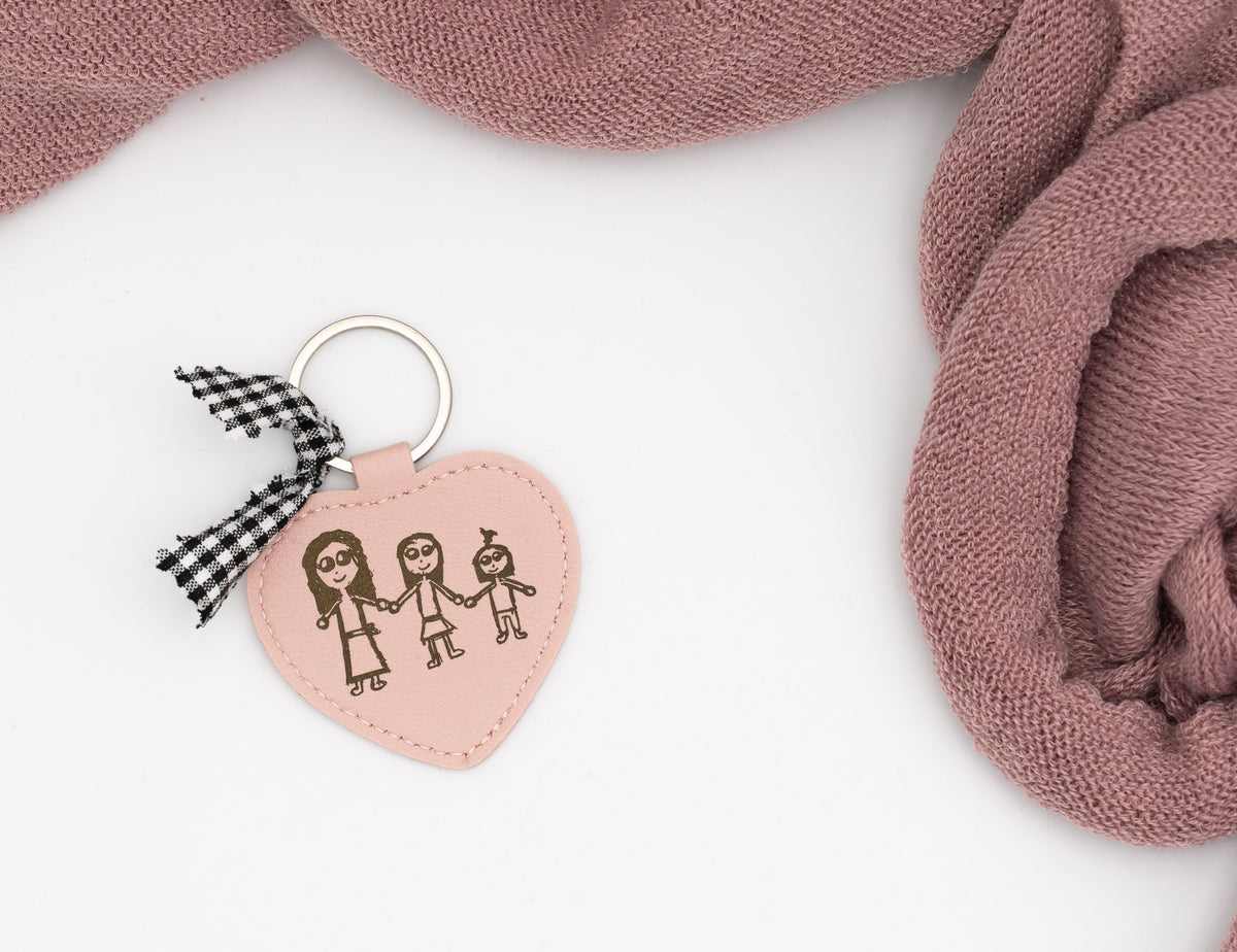 Porte-clé cœur rose avec dessin de trois personnes et nœud vichy noir.