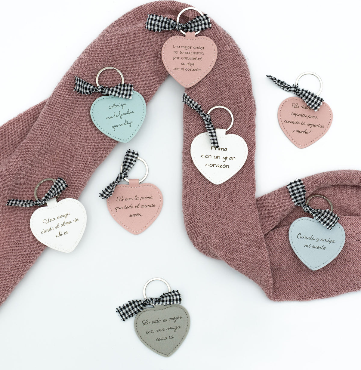 Composition de porte-clés cœur avec messages et nœuds sur un tissu rose.