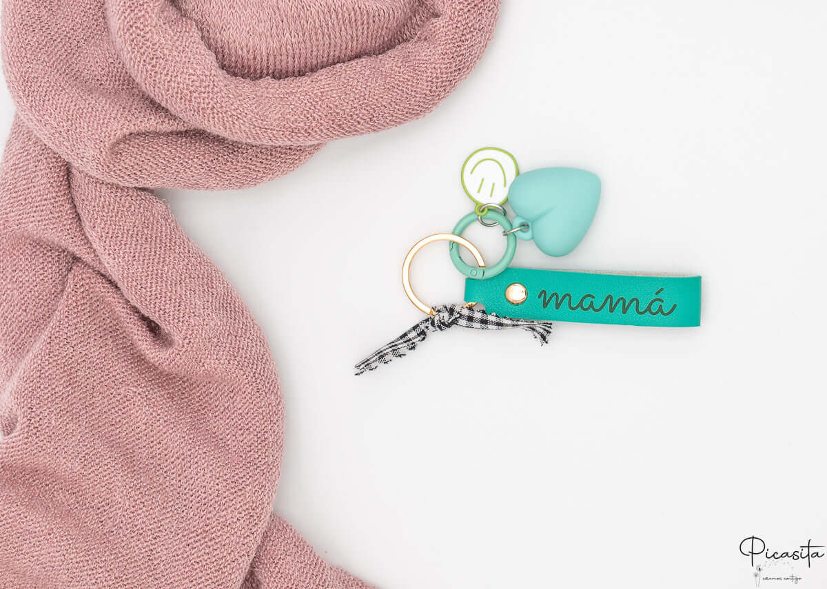 Llavero personalizado color aguamarina con grabado láser, corazón de silicona y carita sonriente metálica.