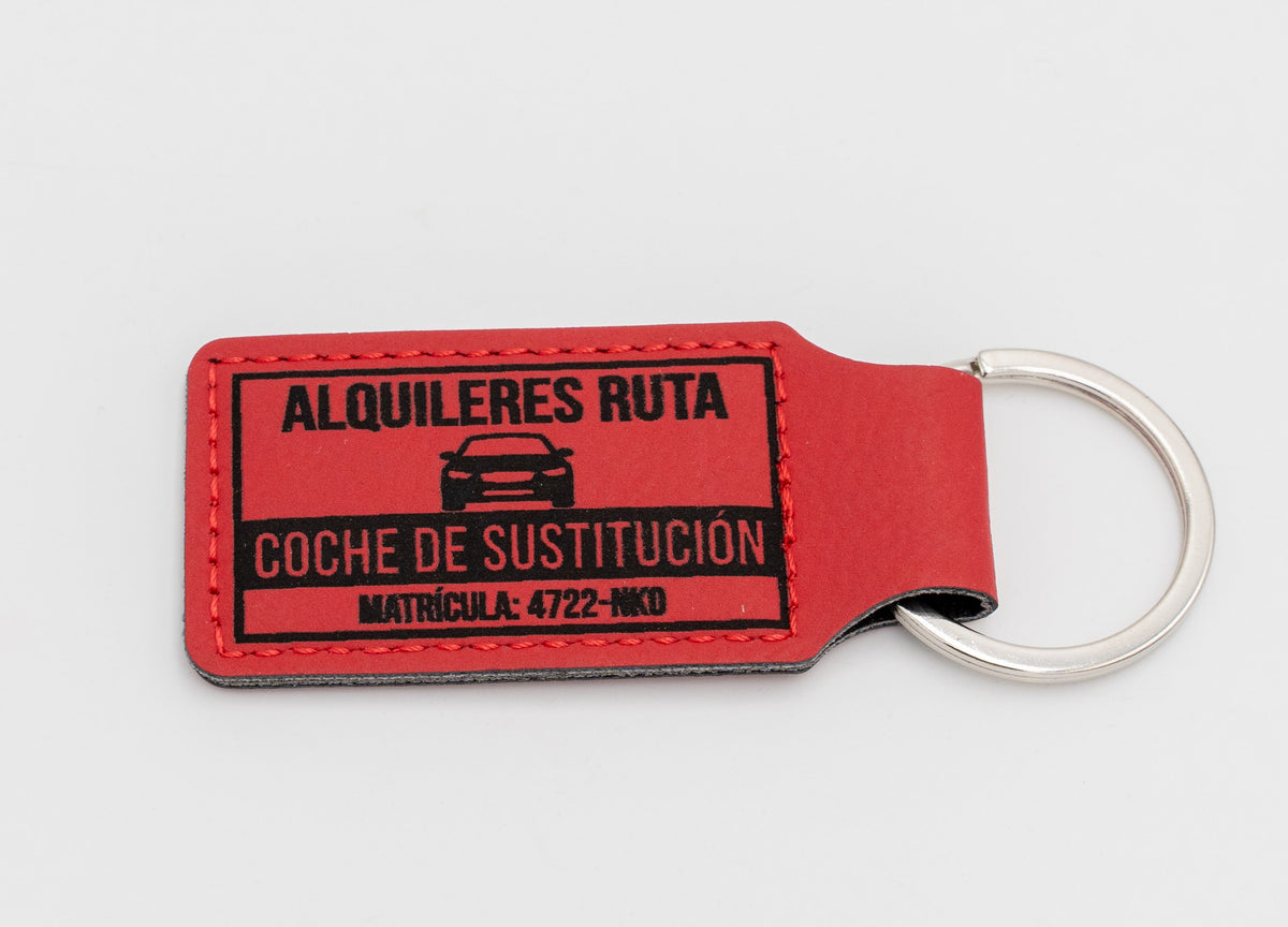 Porte-clé rectangulaire rouge avec texte et dessin de location de véhicules.