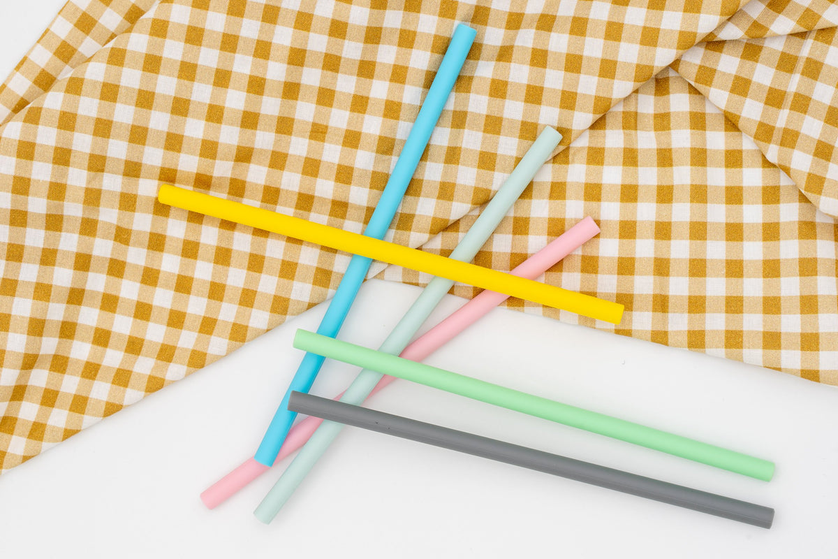 Pailles droites en silicone coloré sur un tissu à carreaux