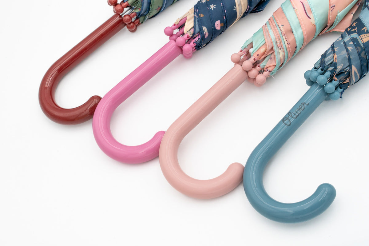 Quatre poignées de parapluie enfant : bordeaux, rose foncé, rose clair et bleu