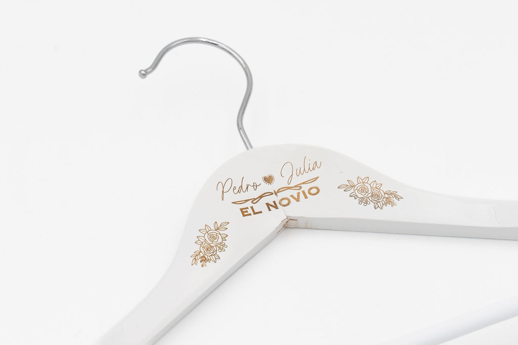 Cintre blanc avec «Pedro ♥ Julia» et «El novio» gravés parmi des fleurs