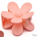 Pinza de pelo con forma de flor en color rosa claro melocotón con diseño de pétalos redondeados.
