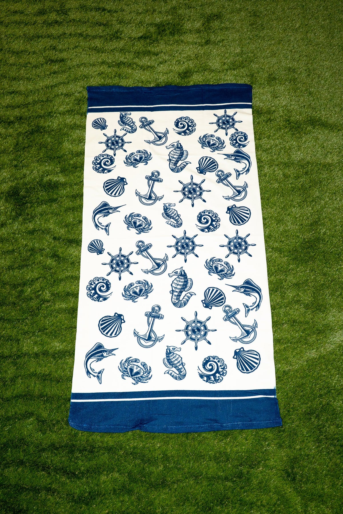 Serviette blanche avec motif marin bleu composé d’ancres, de coquillages et de gouvernails
