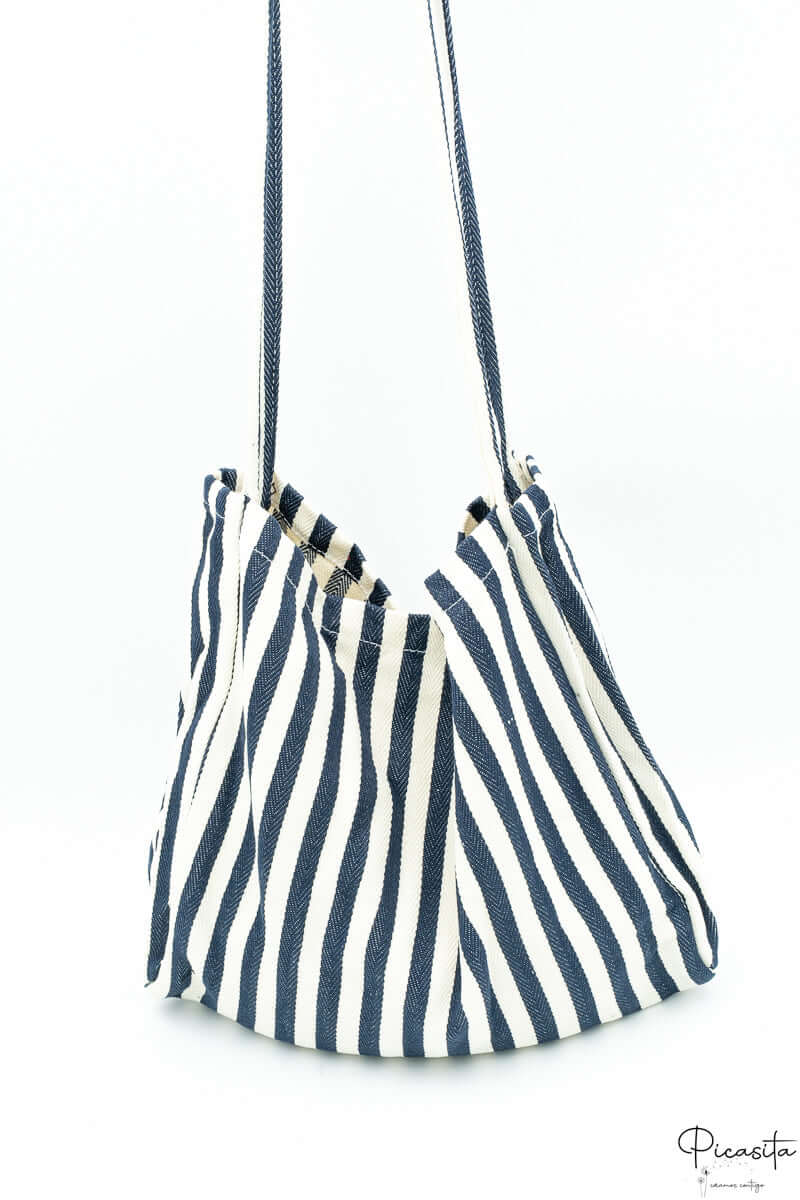 Bolso de algodón con rayas azul marino y blanco visto desde un lateral.