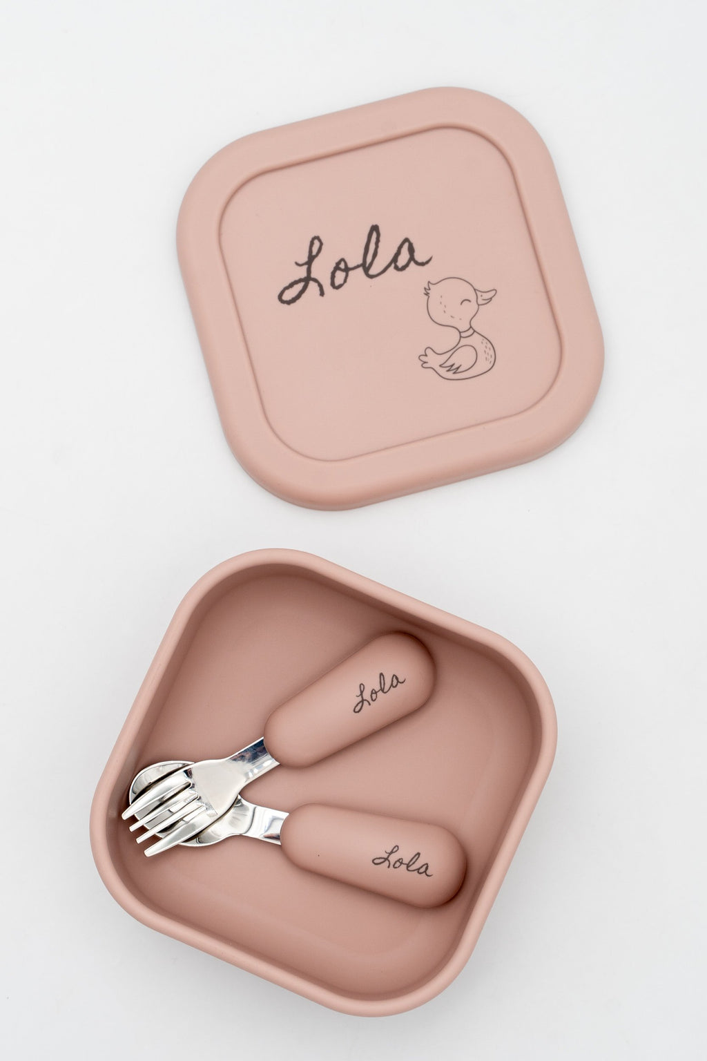 Boîte moyenne rose avec le prénom Lola et un petit canard sur le couvercle, avec des couverts à son nom à l'intérieur