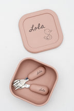 Boîte moyenne rose avec le prénom Lola et un petit canard sur le couvercle, avec des couverts à son nom à l'intérieur